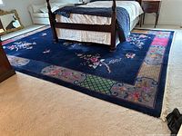 Overhead view of full rug under bed showing central field, border and fringe