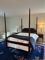 Front view of assembled four poster bed with mattress, bedding and matched nightstands in room