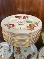 Stack of approximately 10 round plates showing Evesham fruit pattern with cherries, peaches, blackberries, and gold rim.