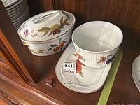 View of three pieces: covered casserole with lid showing vent holes, soufflé dish nested on rectangular serving tray, all featuring Royal Worcester Evesham fruit and leaf design.