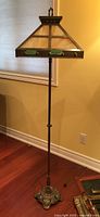 Full view of lamp showing stained glass shade and ornate brass base on hardwood floor