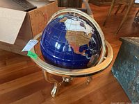 Full view of the semi precious stone globe sitting on its brass base, showing North America and parts of the Atlantic Ocean.