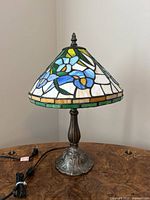 Full view of the stained glass table lamp showing the conical floral shade and metal base.