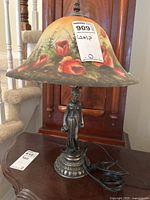 Front view of the table lamp showing the painted floral glass shade and metal figurine base.