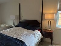 Photo of one of the table lamps lit and visible on nightstand beside a bed with navy and white bedding.