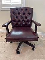 Front view of dark brown faux leather office chair with tufted backrest and padded armrests showing overall condition and style.