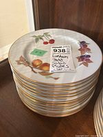 Stack of salad plates showing fruit and leaf patterns with gold trim.