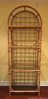 Front view of bamboo style shelving unit showing 4 clear glass shelves and lattice back design with arched top frame.