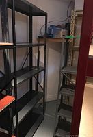 Two metal shelving units, one tall dark metal unit with five shelves and one shorter light gray shelving unit with five shelves.