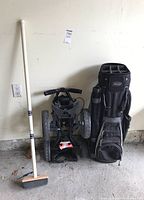 All three items side by side: curling broom, cart, golf bag