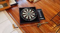 Photo showing the golf club lying on floor next to the Triumph dartboard and several golf balls.