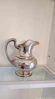 Front view of sterling silver pitcher on shelf