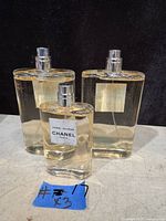 Three Chanel Riviera bottles displayed on surface: two larger behind one smaller