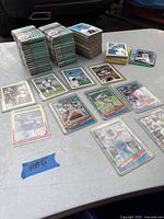 Loose vintage baseball cards displayed with player images visible in protective sleeves or on top of stacks.