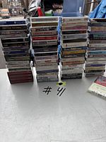 Photo showing multiple stacks of cassette tapes arranged in rows, titles and artists visible on spines
