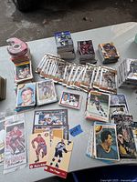 Overview of multiple stacks and packs of NHL hockey cards with visible player faces and team logos, spread on a table.