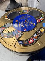 Photo of the gold round metal tin game container with Mickey Mouse ears and Disney character artwork on film reel.