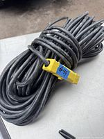 Coiled black heavy duty extension cord with yellow connector.