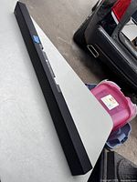 Full length view of the black Samsung sound bar placed on a table, showing its slim rectangular design.