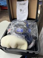 Simoniz random orbit polisher partially wrapped in plastic inside blow molded carrying case with polishing and foam bonnets visible.