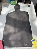 Full view of the RCMP target practice paper silhouette showing humanoid profile and scoring rings, with approximate size visible relative to nearby objects.