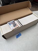 Open cardboard box filled with stacked vintage hockey cards from the 1990-1991 Upper Deck set, showing many white-bordered cards with one card featuring a player on top.