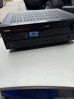 Front and top view of Yamaha AV receiver showing power lights and multiple input buttons.