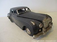 Front angled view of black metal toy car showing details of grille, headlights and wear