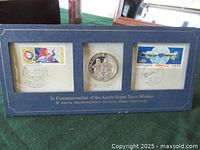 Full desktop presentation frame showing the sterling silver medallion in center flanked by two first day covers with stamps and cancellations, blue border frame