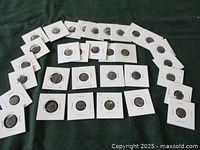 Overview of 32 coins arranged on cloth surface
