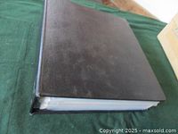 Closed black binder lying on green cloth surface