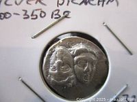 Close up photo of the ancient silver drachm coin showing the two heads of youth on the obverse side with detailed facial features.