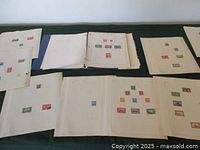 Overview of multiple album pages laid out showing Canadian stamps on white printed pages, some with several stamps of different colors and sizes.