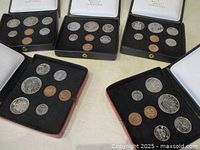 Five Royal Canadian Mint coin sets displayed in black and red velvet interior cases with white lids featuring gold Royal Canadian Mint logos.