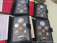 Four Royal Canadian Mint double silver dollar currency sets for the years 1982 through 1985 displayed on a table, showing the coins in protective black cases.