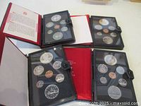 Overview photo showing the four coin sets in protective cases with some presented in red folders.