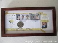 Framed memorial first day cover showing five Lady Diana stamps and a five pound coin in a wooden frame with glass