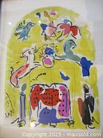 Close-up photo of the colorful original lithograph artwork by Marc Chagall featuring abstract design with animals and symbolic figures on yellow-green background.