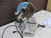 Front angle view of the Delta Shop Master chop saw showing the blade, handle, and power cord on a white table.