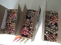 Overhead view of three open boxes filled with paper-wrapped rolls of Canadian pennies