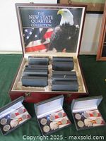 Boxed wooden case open showing 12 sets of state quarters in plastic holders.