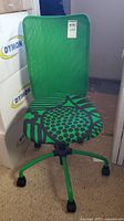Front view of the green mesh desk chair showing patterned seat and five caster wheels.