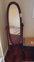 Front view of cheval floor mirror showing entire mirror and wooden frame.