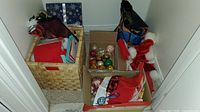 Boxes and basket containing assorted Christmas decorations, including stockings and wrapped items