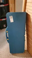 Photo shows folded rectangular blue plastic picnic table as a closed rectangular case with carrying handle on the side.