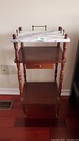 Front view of the wooden side table showing marble top, small drawer, and bottom shelf