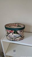 Decorative oval sewing kit storage box showing winter holiday village scene on exterior