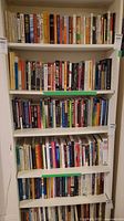 Front view of white adjustable bookshelf filled with various books on multiple shelves.