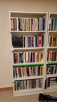 Full view of white bookshelf filled with books on six shelves.
