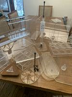 Image showing varied sizes and types of clear acrylic display boxes and stands arranged on a wooden table.